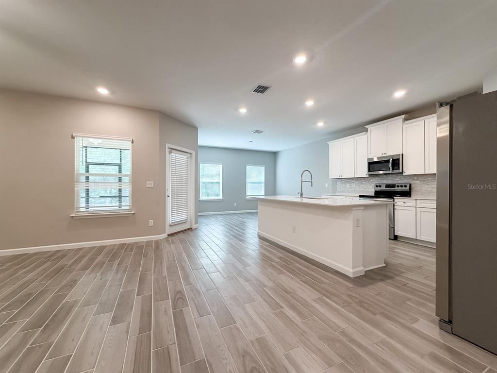 A kitchen with white cabinets and a center island opens into a living area — 2258 NW 89TH WAY, GAINESVILLE, FL