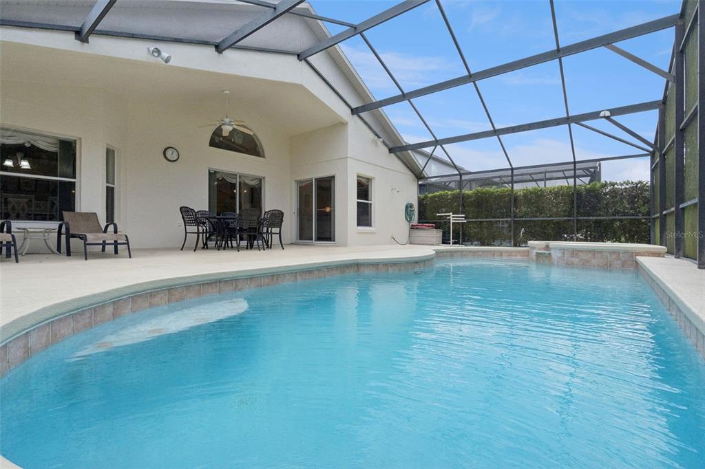A screened-in patio features a swimming pool, outdoor dining furniture, and a ceiling fan — 4706 CUMBRIAN LAKES DRIVE, KISSIMMEE, FL