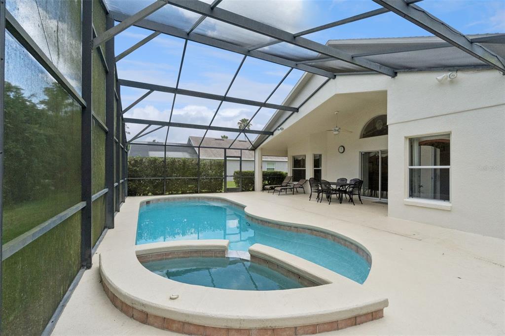 A screened-in patio features a swimming pool with an attached spa and outdoor dining furniture — 4706 CUMBRIAN LAKES DRIVE, KISSIMMEE, FL