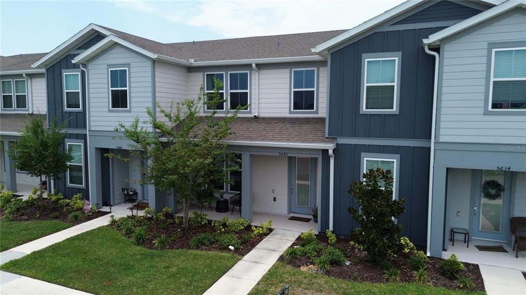 A two-story townhouse exterior features blue and light gray siding with a covered entryway — 5640 PINELAND RUN, ORLANDO, FL