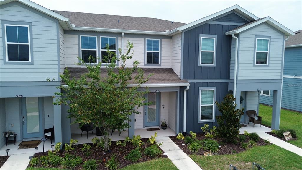 An exterior view of a multi-unit townhouse building with light and dark blue siding — 5640 PINELAND RUN, ORLANDO, FL