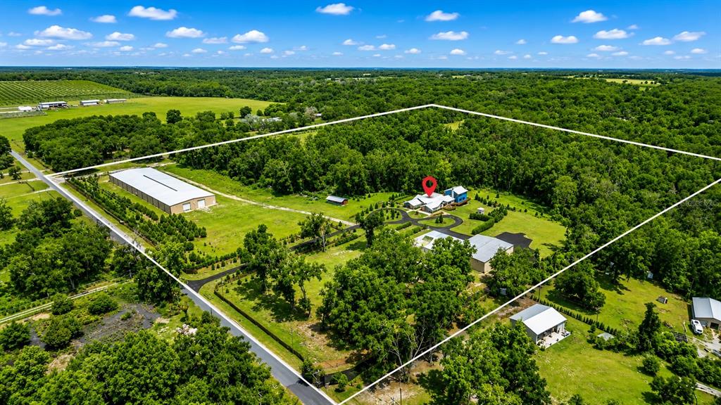 An aerial view shows a large property with a house, outbuildings, and surrounding forest — 27255 HICKORY HILL ROAD, BROOKSVILLE, FL