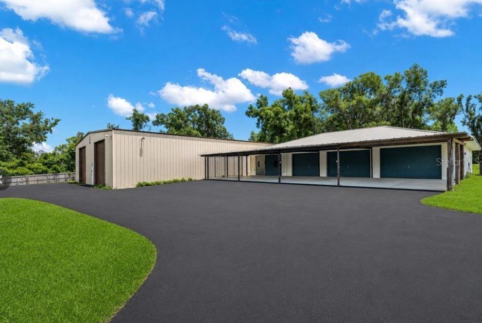 A large metal workshop building with a covered carport and multiple garage doors — 27255 HICKORY HILL ROAD, BROOKSVILLE, FL
