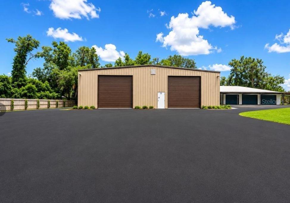 A tan metal warehouse building with two large roll-up doors sits on a paved lot — 27255 HICKORY HILL ROAD, BROOKSVILLE, FL