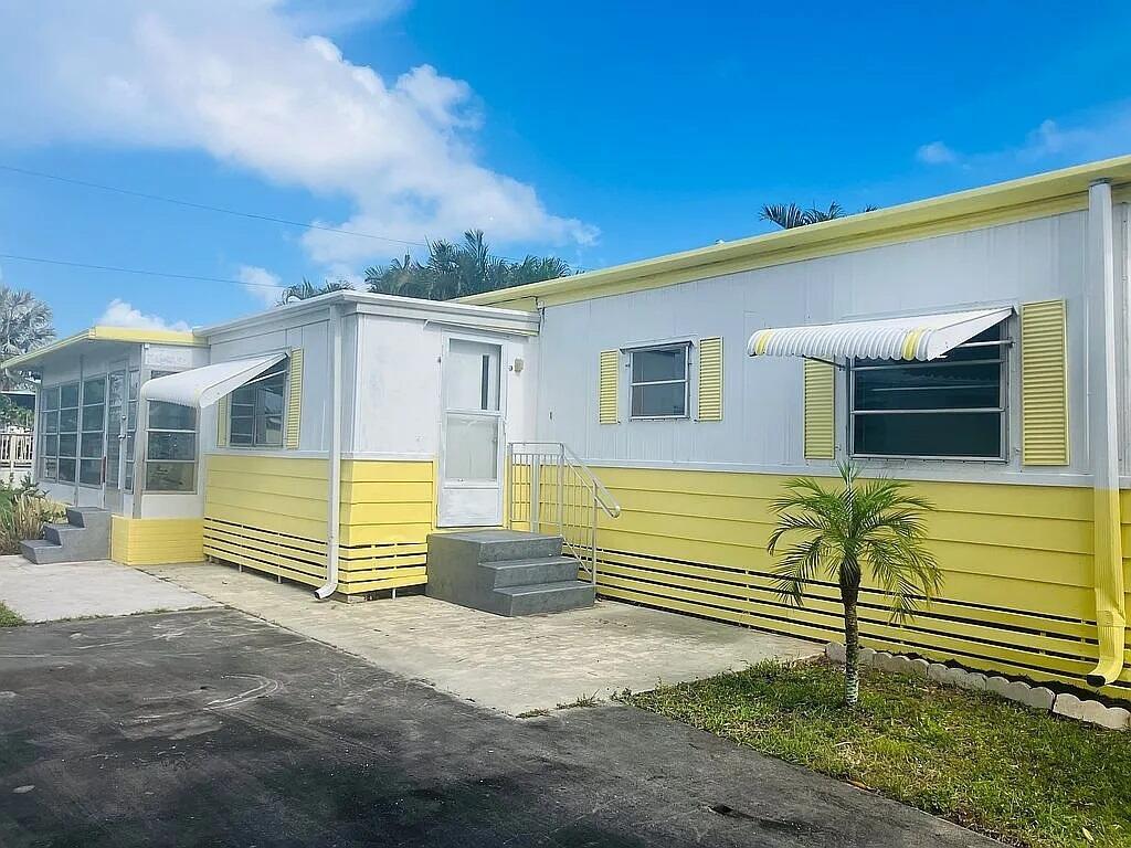 A yellow and white mobile home features a concrete driveway, stairs, and a small palm tree — 4054 Marigold Road, Boynton Beach FL 33436, BOYNTON BEACH, FL