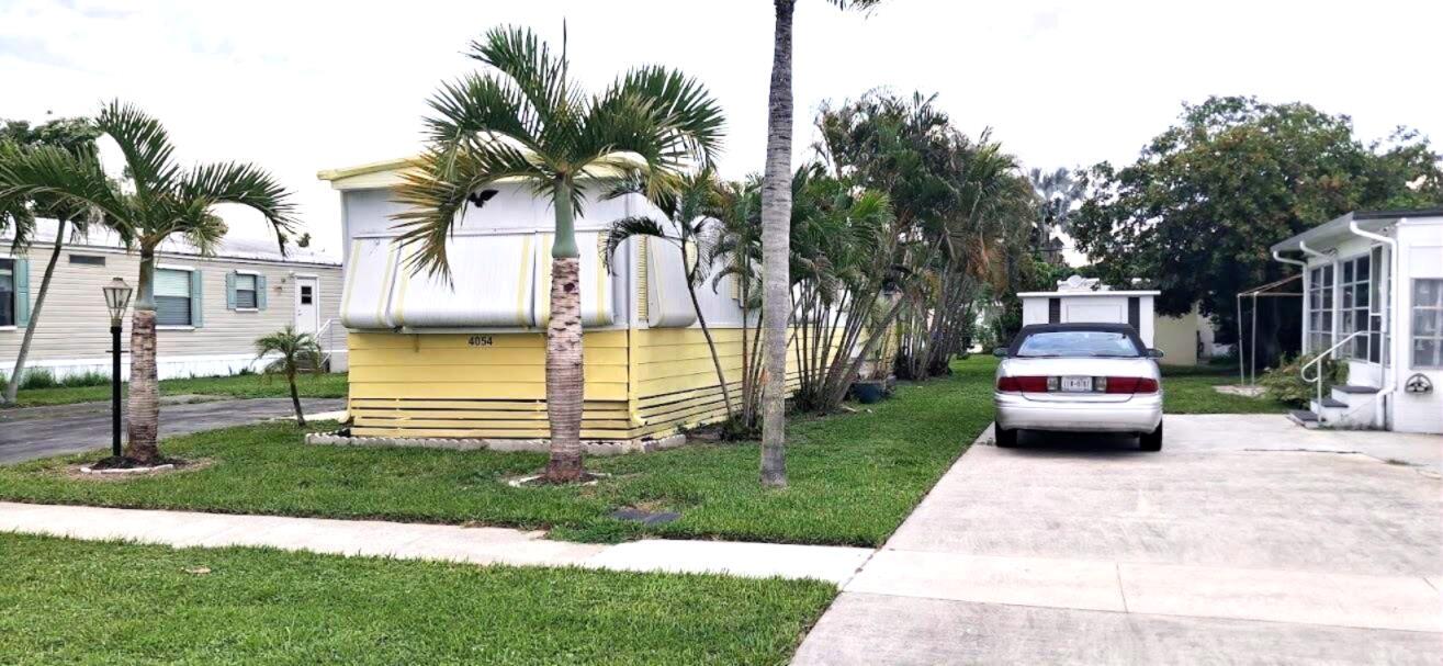 A yellow mobile home with palm trees and a car parked in the driveway — 4054 Marigold Road, Boynton Beach FL 33436, BOYNTON BEACH, FL