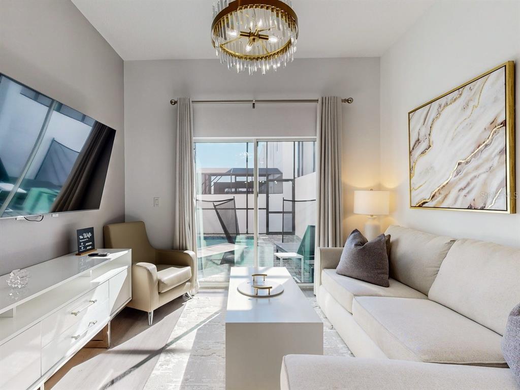 A living room features a white sofa, a television, a coffee table, and sliding glass doors — 605 TRIKOMO DRIVE, DAVENPORT, FL