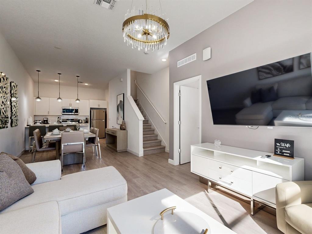A living room with a large television, white media console, and an adjacent dining area — 605 TRIKOMO DRIVE, DAVENPORT, FL