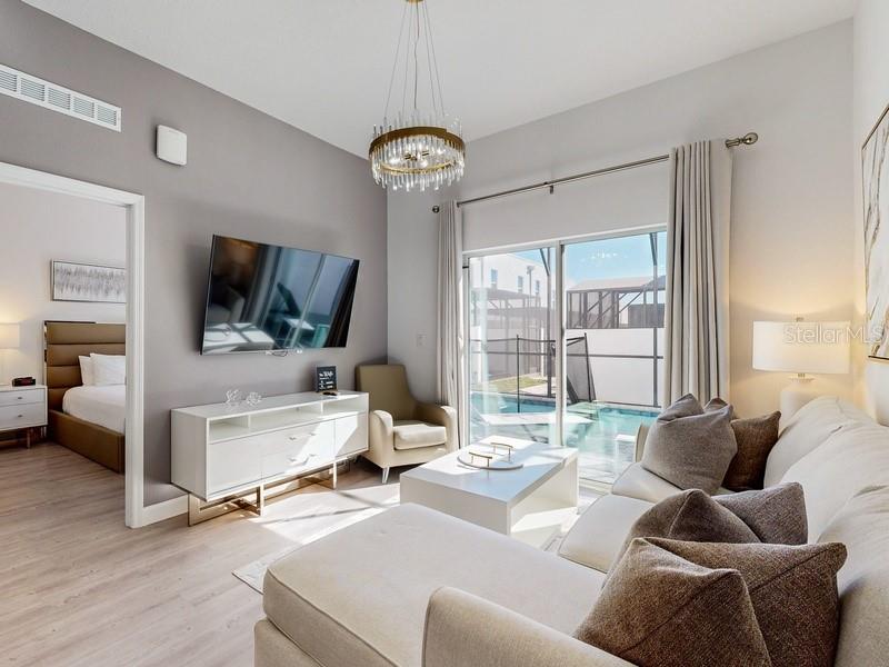 A living room features a sectional sofa, a white media console, and a sliding glass door — 605 TRIKOMO DRIVE, DAVENPORT, FL