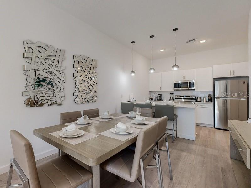 A dining area with a wooden table and chairs sits adjacent to a modern kitchen — 605 TRIKOMO DRIVE, DAVENPORT, FL