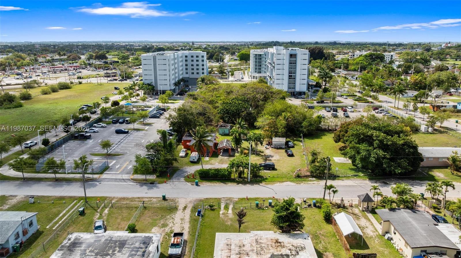 An aerial view shows a residential property with a small house, parking lots, and buildings — 11870 SW 214th St, Miami FL 33177, MIAMI, FL