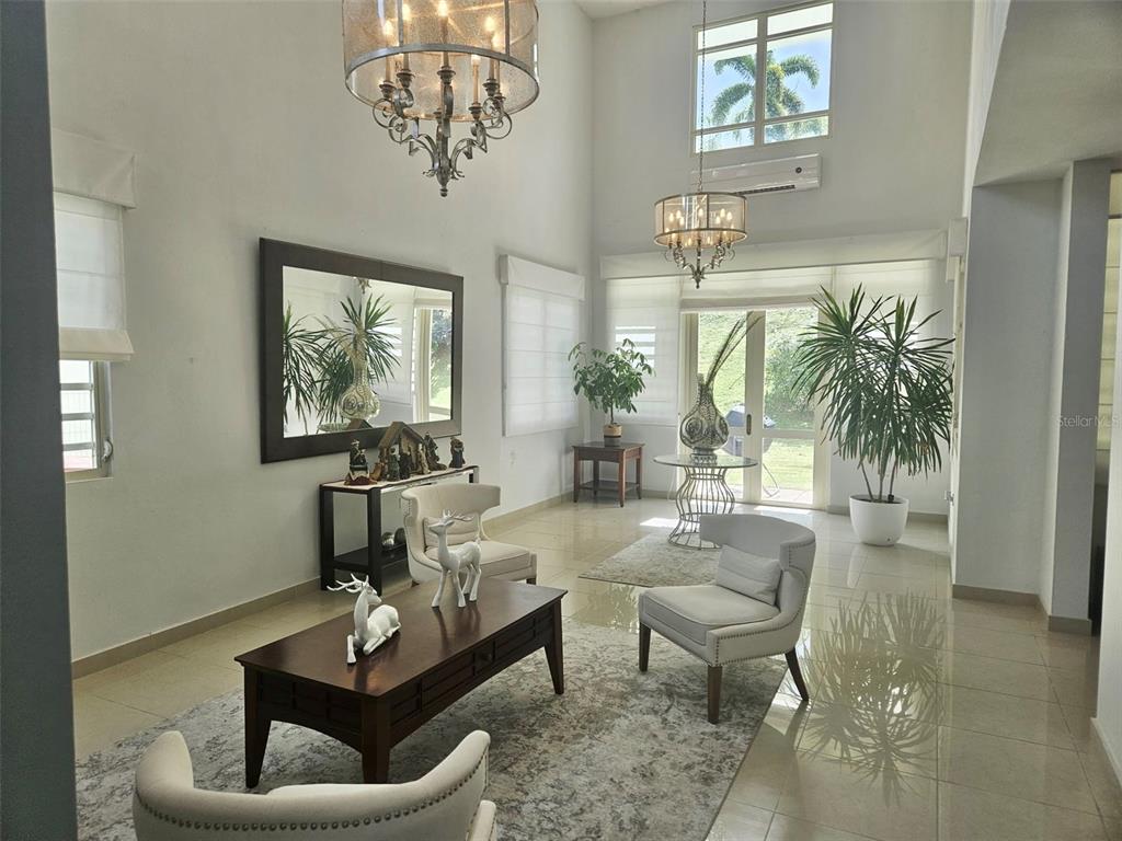 A bright, high-ceilinged living room features tile floors, two chandeliers, and a large mirror — H 11 CAGUAS REAL, TORRES DEL ORO, CAGUAS, PR