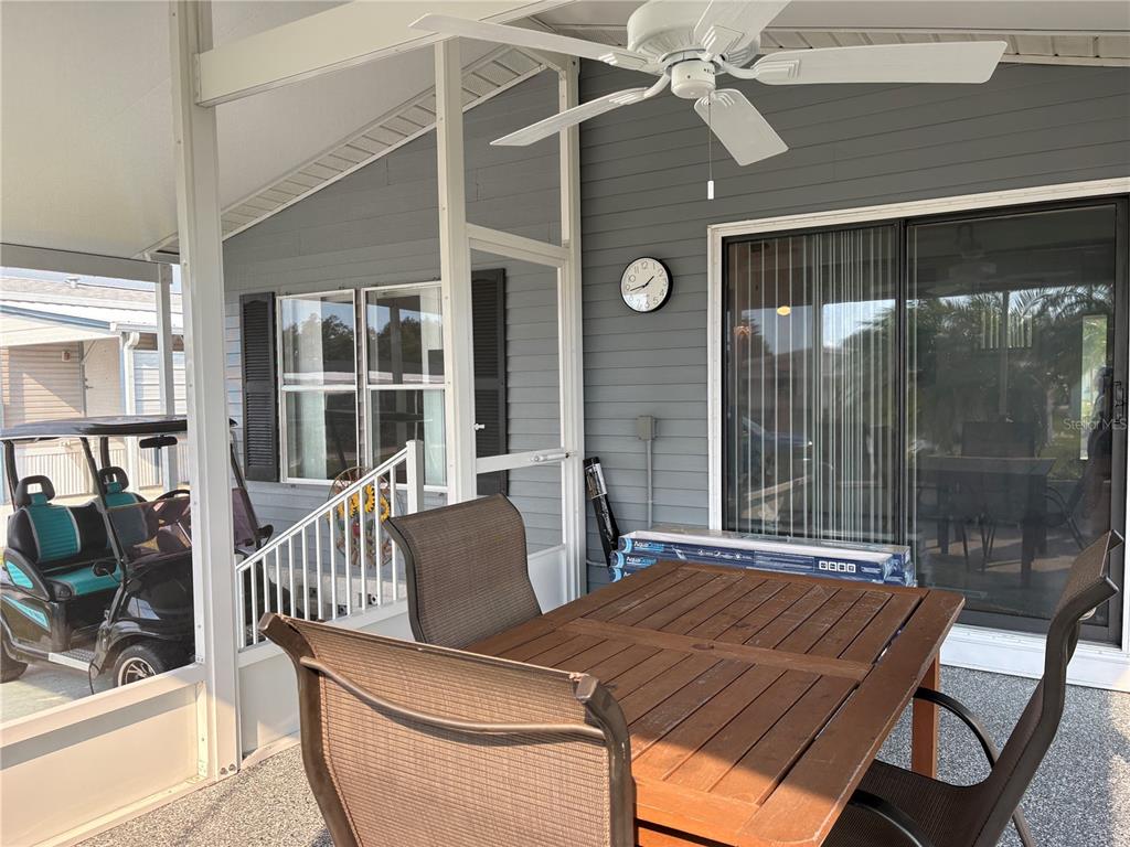 A covered patio features a wooden dining table, a ceiling fan, and a golf cart — 5696 HOLIDAY PARK BOULEVARD, NORTH PORT, FL