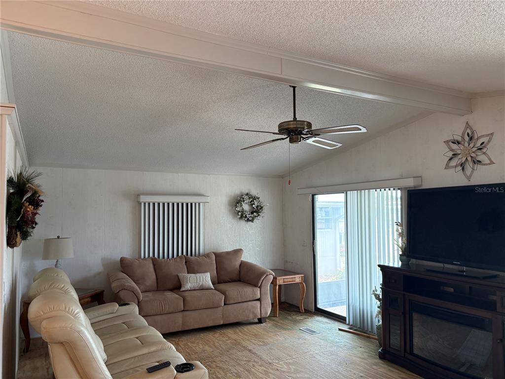 A living room features a brown sofa, a cream recliner, and a ceiling fan — 5696 HOLIDAY PARK BOULEVARD, NORTH PORT, FL