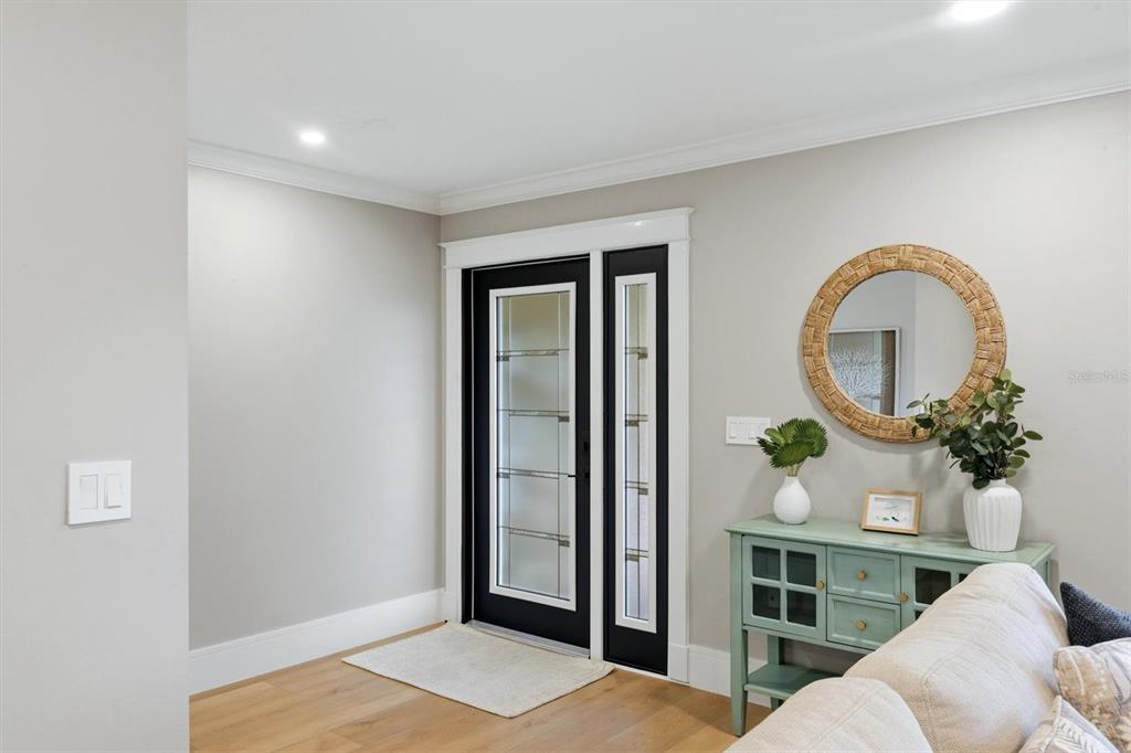 A bright entryway features a black-framed glass door, light wood flooring, and a console table — 5159 OAKMONT PLACE, SARASOTA, FL