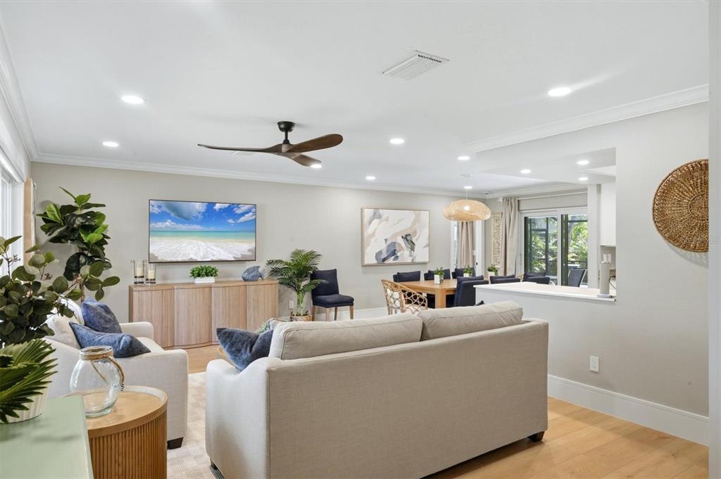 A living room with a beige sofa, television, dining area, and light wood flooring — 5159 OAKMONT PLACE, SARASOTA, FL