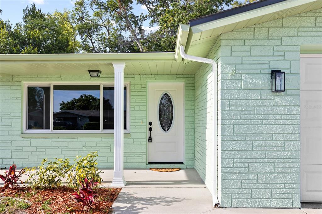 A light green stone-veneer house exterior features a white front door and a covered porch — 6239 7TH AVENUE, NEW PORT RICHEY, FL