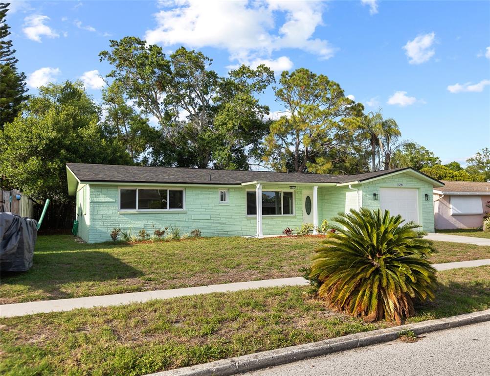 A single-story house with light green stone siding, a dark roof, and a front lawn — 6239 7TH AVENUE, NEW PORT RICHEY, FL