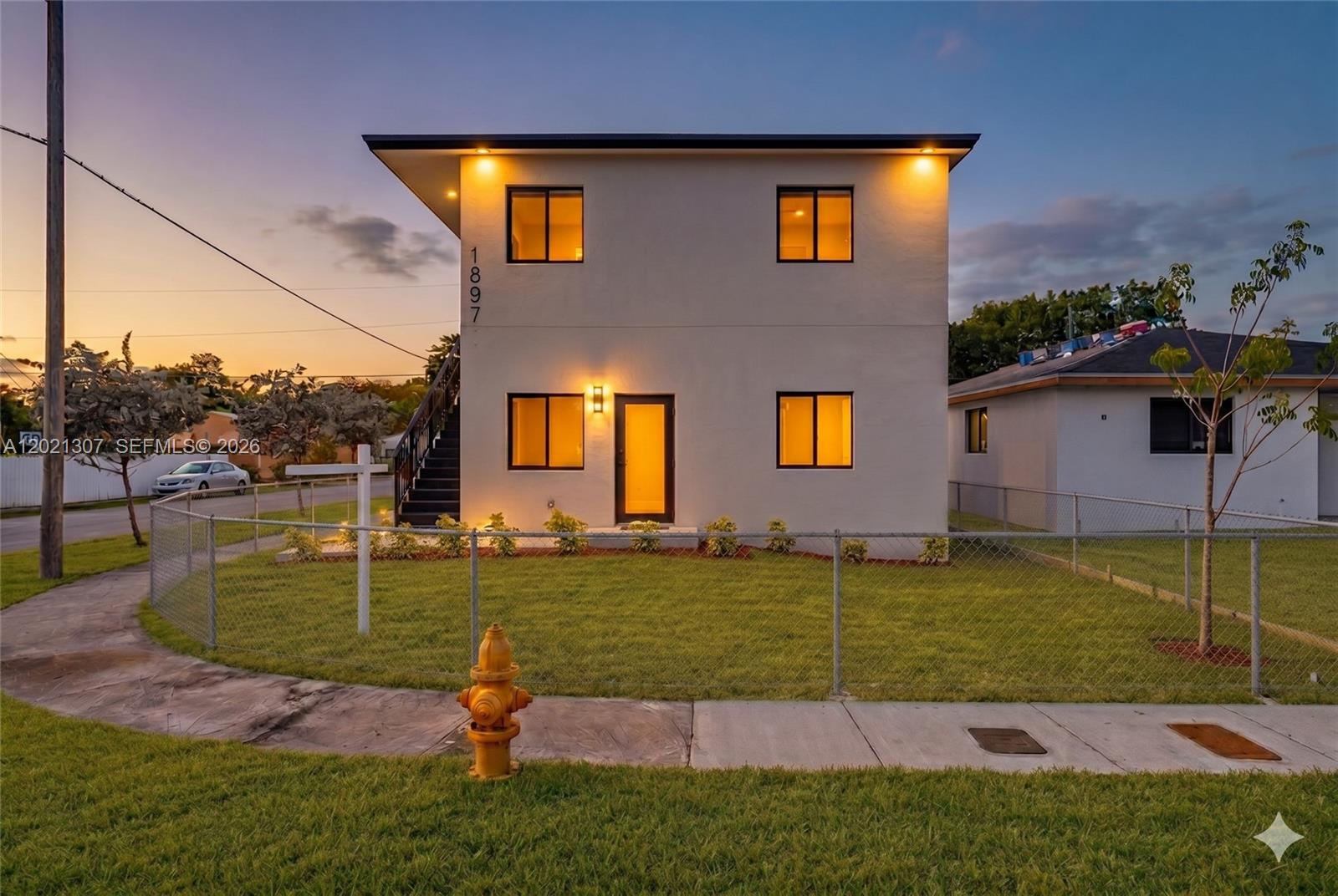 A two-story house with a flat roof, exterior staircase, and a fire hydrant in front — 1895 NW 47th Ter, Miami FL 33142, MIAMI, FL