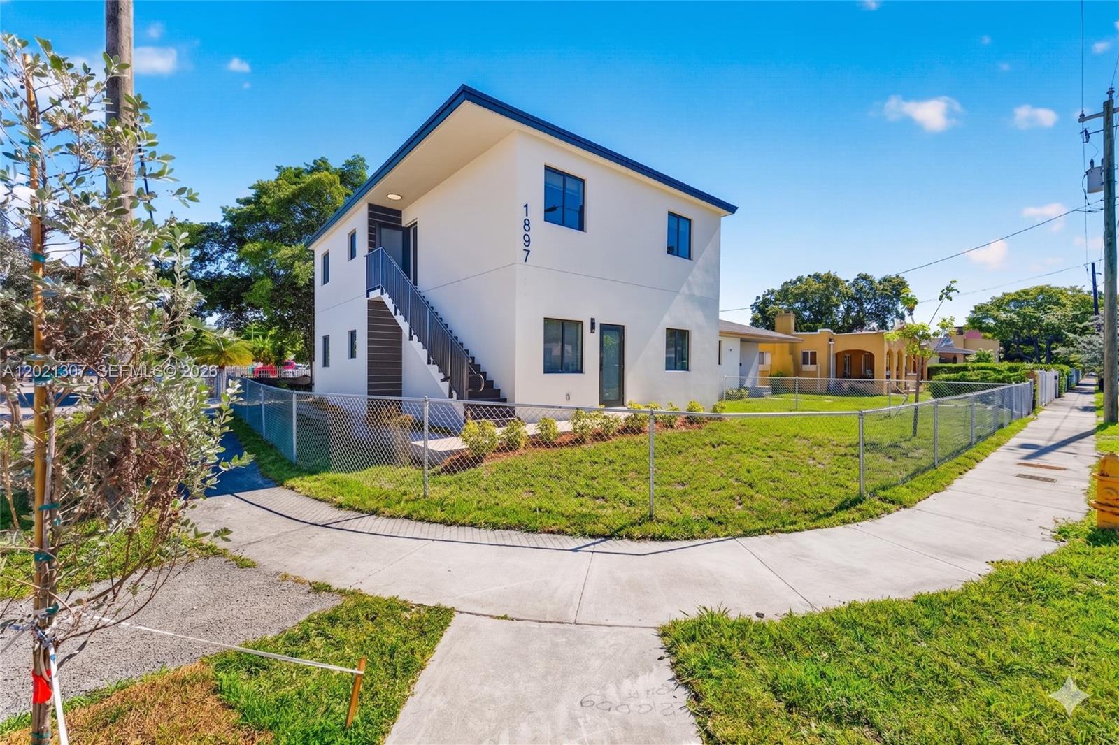 A two-story white building with an exterior staircase stands on a corner lot — 1895 NW 47th Ter, Miami FL 33142, MIAMI, FL