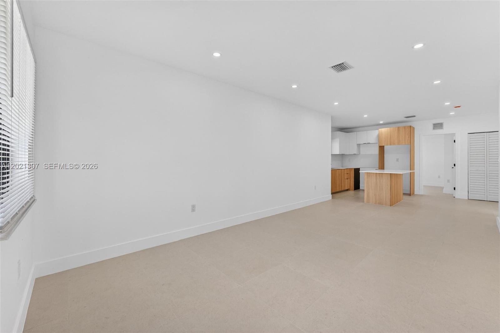 An open-concept room features white walls, light tile flooring, and a modern kitchen area — 1895 NW 47th Ter, Miami FL 33142, MIAMI, FL