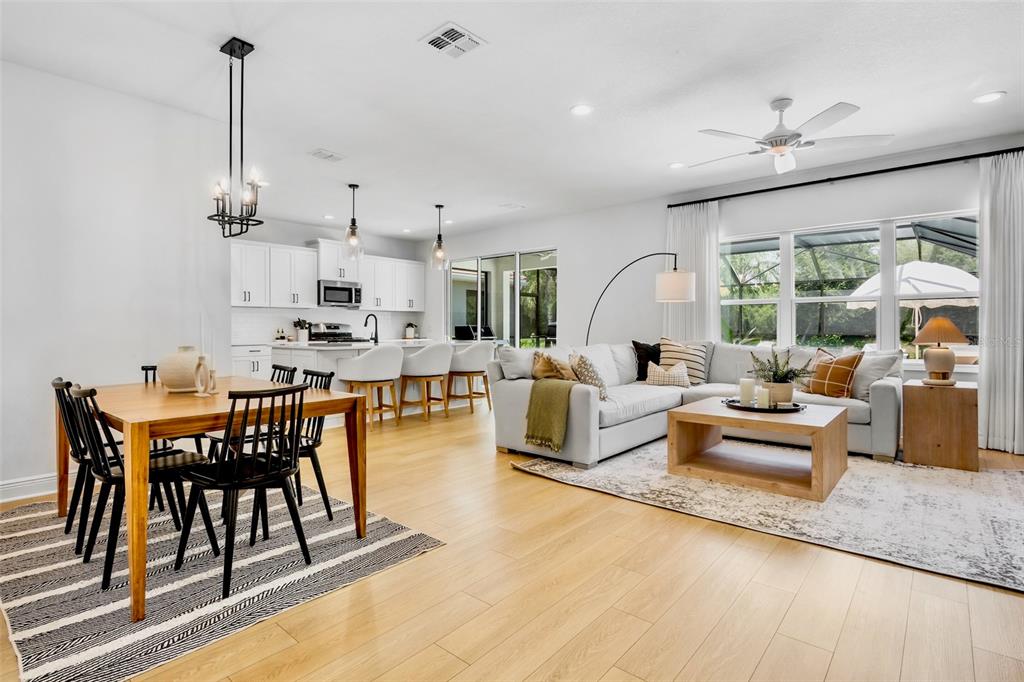 An open-concept living and dining area features light wood flooring, white cabinetry, and neutral furniture — 10113 CANAVERAL CIRCLE, SARASOTA, FL