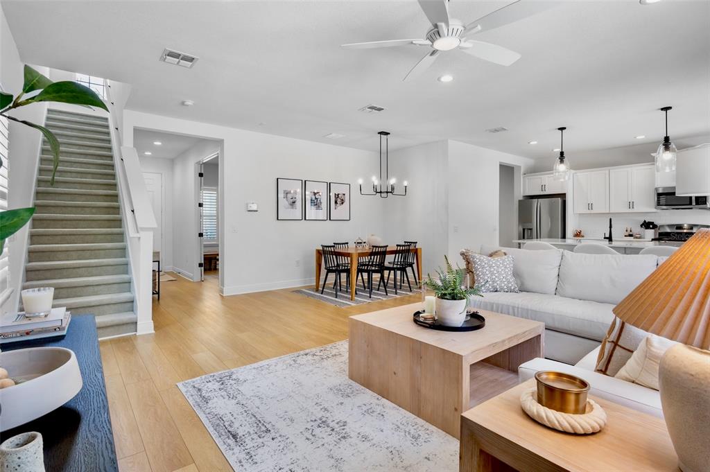 An open-concept living room and dining area with light wood floors and a staircase — 10113 CANAVERAL CIRCLE, SARASOTA, FL