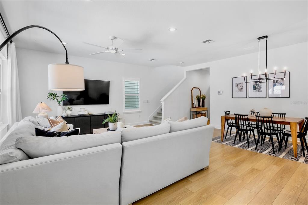 An open-concept living and dining area features light wood floors, white walls, and modern furniture — 10113 CANAVERAL CIRCLE, SARASOTA, FL