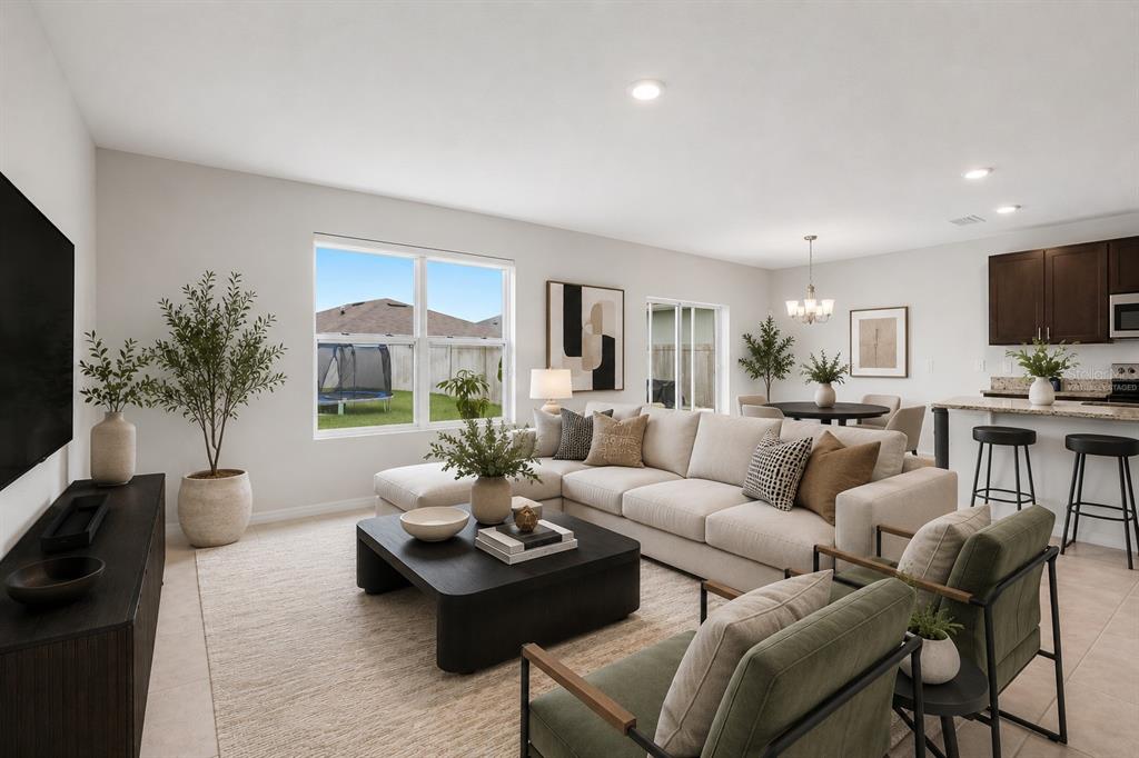 A living room with a sectional sofa, two green armchairs, and an open kitchen area — 5125 FIDDLEWOOD WAY, ST CLOUD, FL
