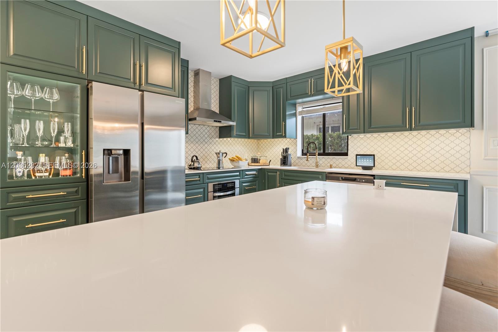 A modern kitchen features dark green cabinets, gold hardware, a white island, and stainless appliances — 1302 Fillmore St, Hollywood FL 33019, HOLLYWOOD, FL
