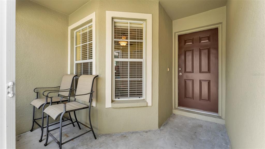 A covered porch features two chairs, two windows, and a brown front door — 3182 WINCHESTER ESTATES LOOP, LAKELAND, FL
