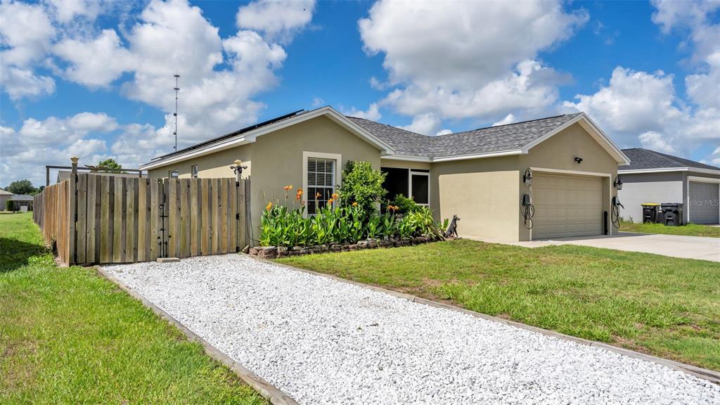 A single-story house with a white gravel driveway, wooden fence, and attached two-car garage — 3182 WINCHESTER ESTATES LOOP, LAKELAND, FL