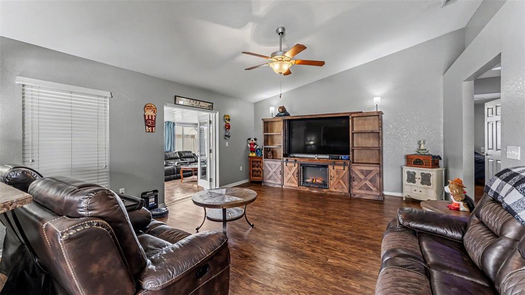 A living room features brown leather furniture, a large entertainment center with a fireplace, and wood-look flooring — 3182 WINCHESTER ESTATES LOOP, LAKELAND, FL