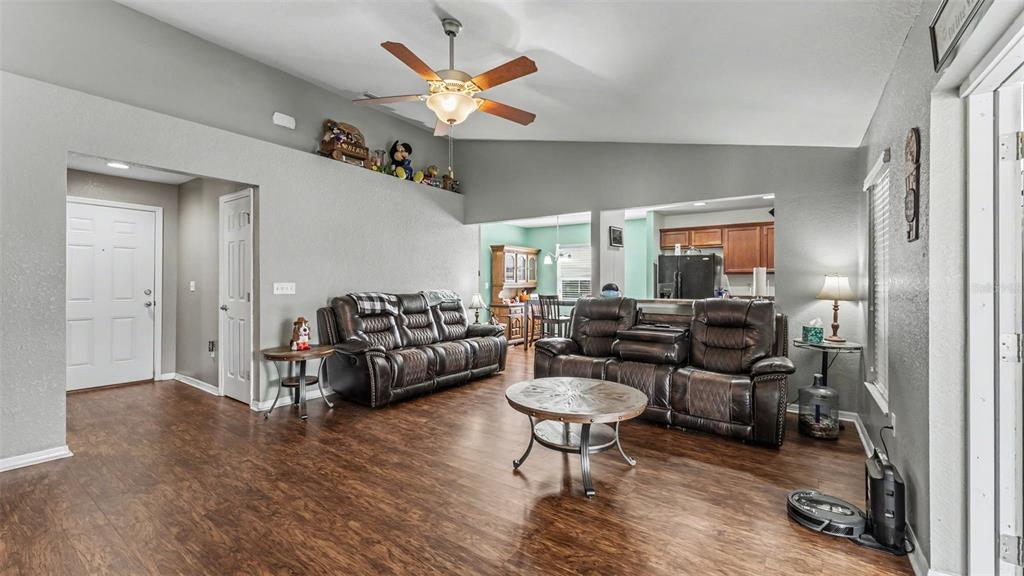 A living room features dark leather sofas, a round coffee table, and wood-look flooring — 3182 WINCHESTER ESTATES LOOP, LAKELAND, FL