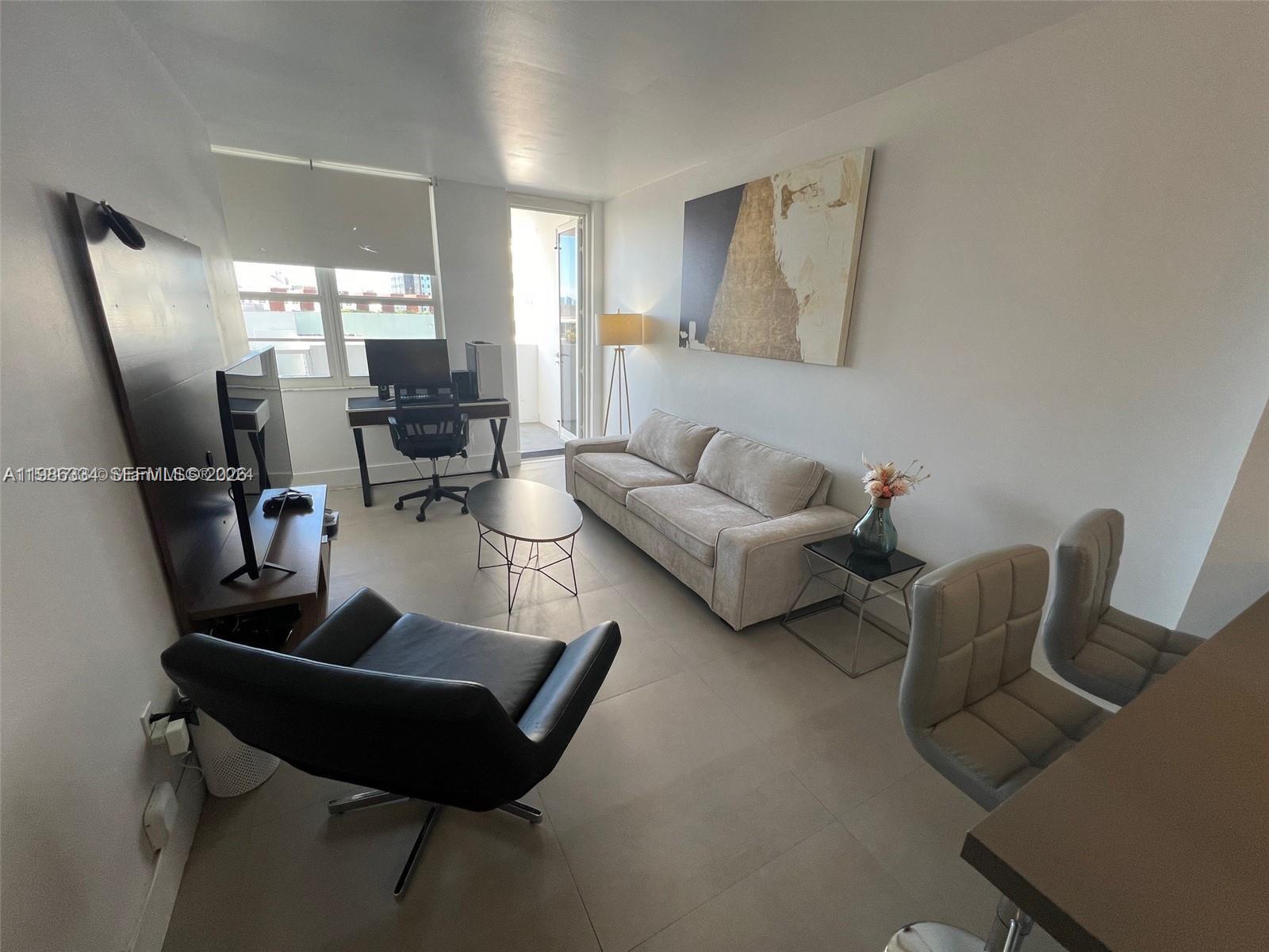 A modern living room features a sofa, desk, armchair, and tile flooring — 100 Lincoln Rd # 620, Miami Beach FL 33139, MIAMI BEACH, FL
