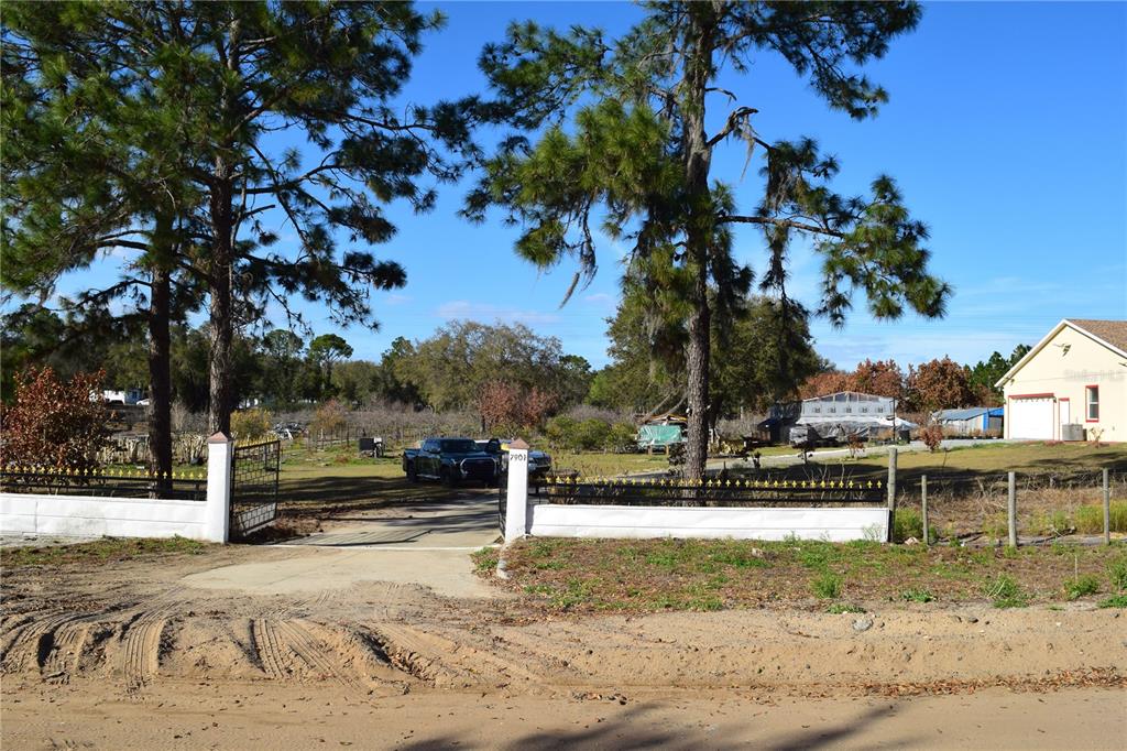 A gated driveway leads to a large, open lot with trees and a parked truck — 7901 N CHERRY LAKE GROVES ROAD, GROVELAND, FL