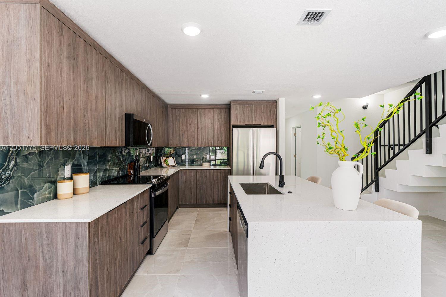 A modern kitchen features wood-grain cabinets, a white quartz island, and a green marble backsplash — 522 NW 14 CT, Florida City FL 33034, FLORIDA CITY, FL