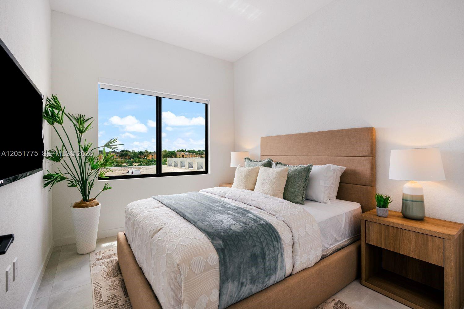 A bedroom features a tan upholstered bed, a large window, and a potted plant — 522 NW 14 CT, Florida City FL 33034, FLORIDA CITY, FL