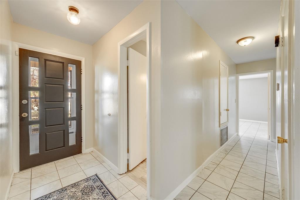An entryway with a dark brown front door, white tile floors, and a hallway beyond — 1148 N SINGLETON AVENUE, TITUSVILLE, FL