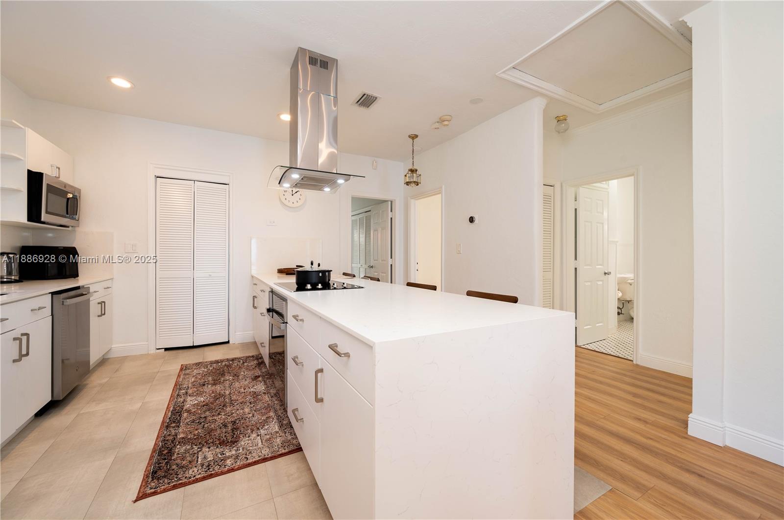 A modern kitchen features white cabinetry, a large central island, and stainless steel appliances — 501 SW 24th Rd # 501, Miami FL 33129, MIAMI, FL