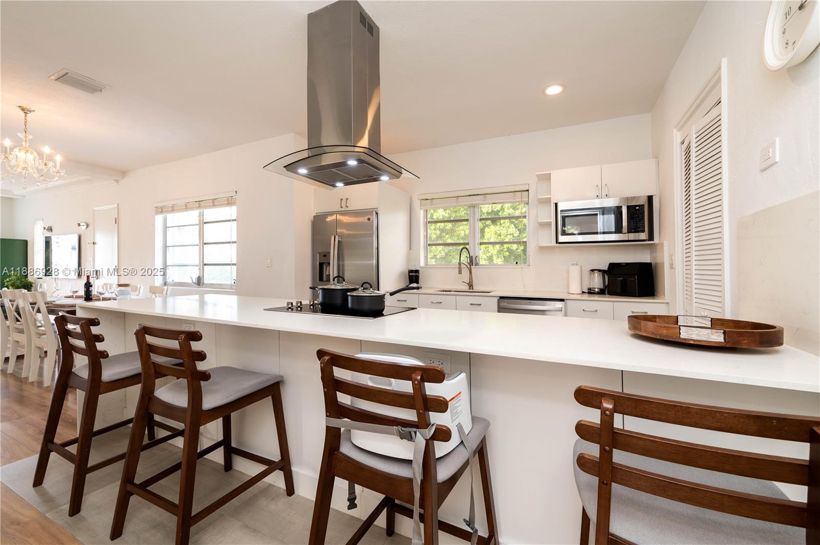 A modern kitchen features a white island with bar stools, stainless appliances, and a range hood — 501 SW 24th Rd # 501, Miami FL 33129, MIAMI, FL