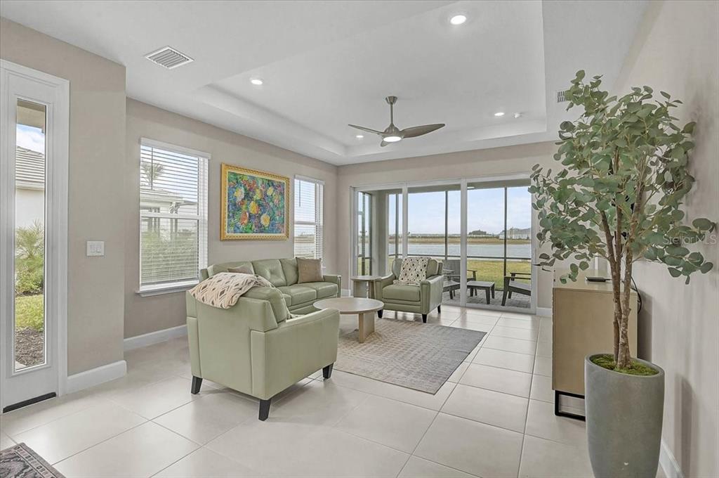 A living room features light tile floors, a tray ceiling, and sliding doors to a patio — 7782 WANING MOON WAY, SARASOTA, FL