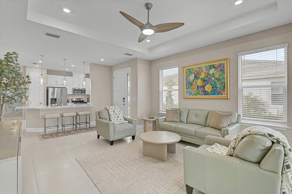 A living room with light-colored furniture, a ceiling fan, and an adjacent kitchen area — 7782 WANING MOON WAY, SARASOTA, FL