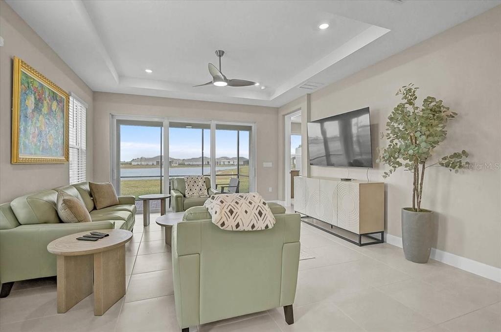 A living room features light green furniture, a television console, and a view of water — 7782 WANING MOON WAY, SARASOTA, FL