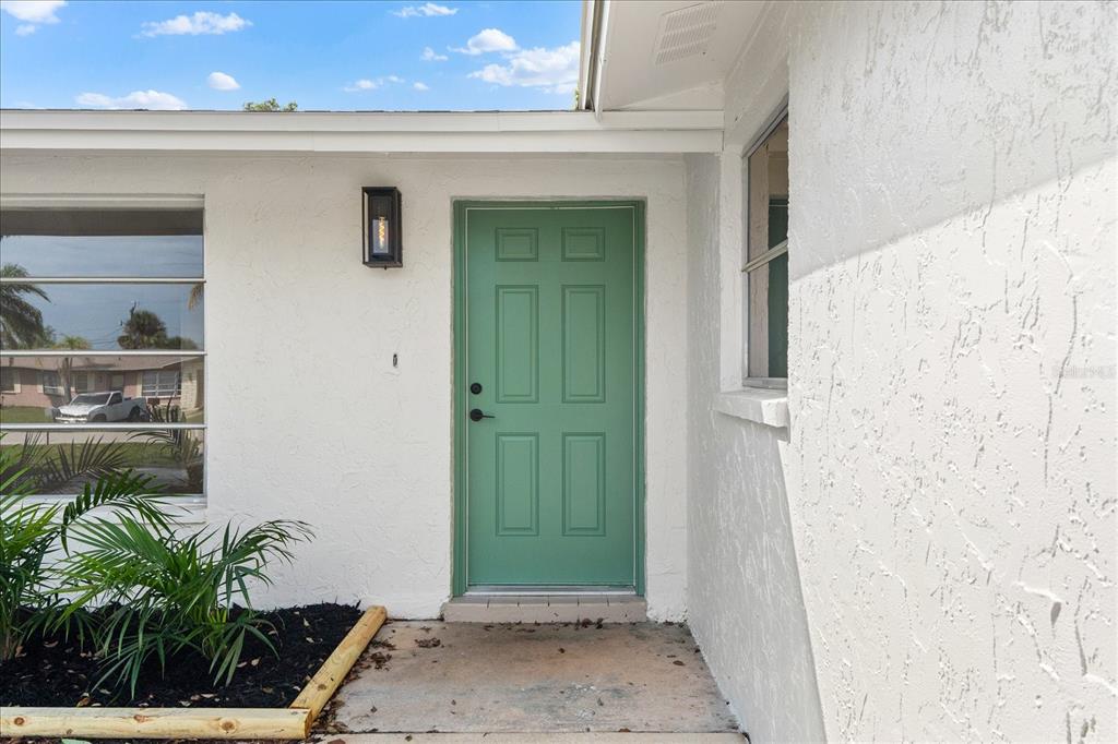 A green front door is centered on the white stucco exterior of a house — 3445 GULF LANE, ROTONDA WEST, FL