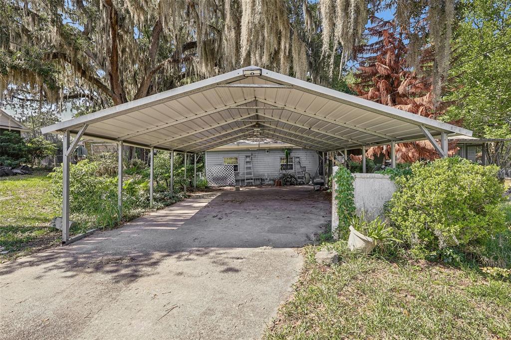 A metal carport stands over a concrete driveway in front of a single-story house — 2315 EDGEWATER AVENUE, LEESBURG, FL