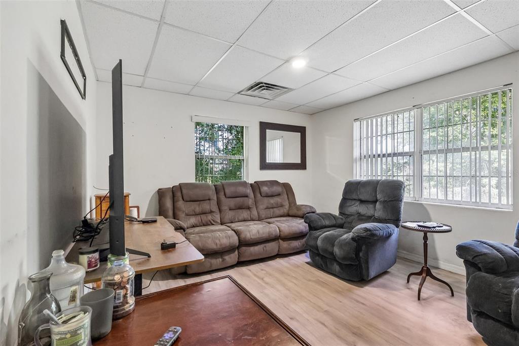A living room features a brown sofa, a gray recliner, and a television on a stand — 2315 EDGEWATER AVENUE, LEESBURG, FL