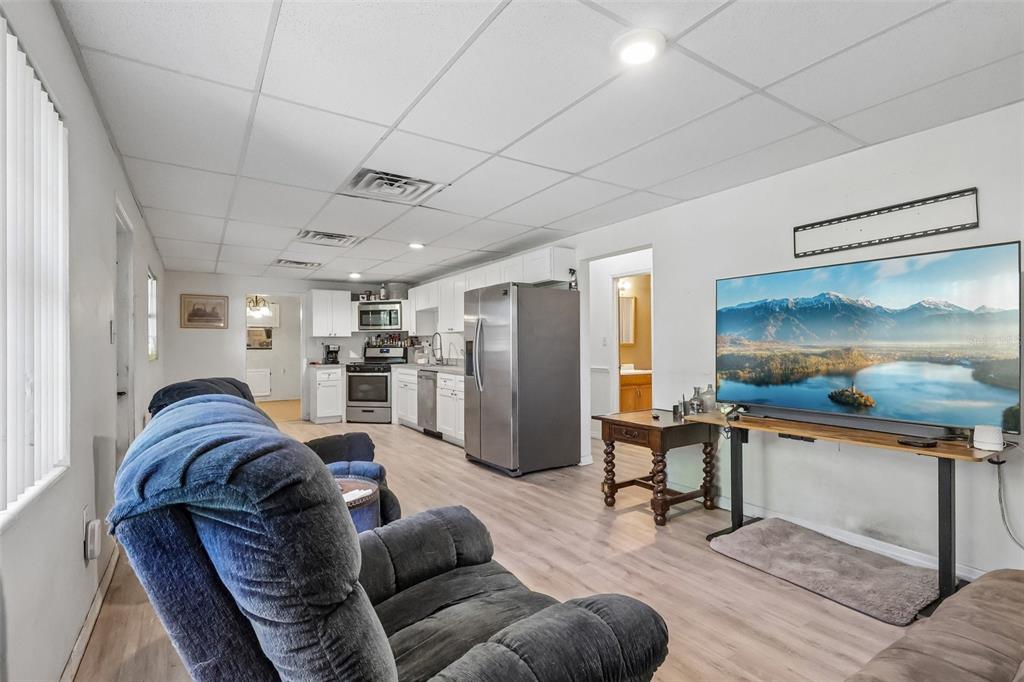A living room with a recliner, a television, and an open-concept kitchen with white cabinets — 2315 EDGEWATER AVENUE, LEESBURG, FL