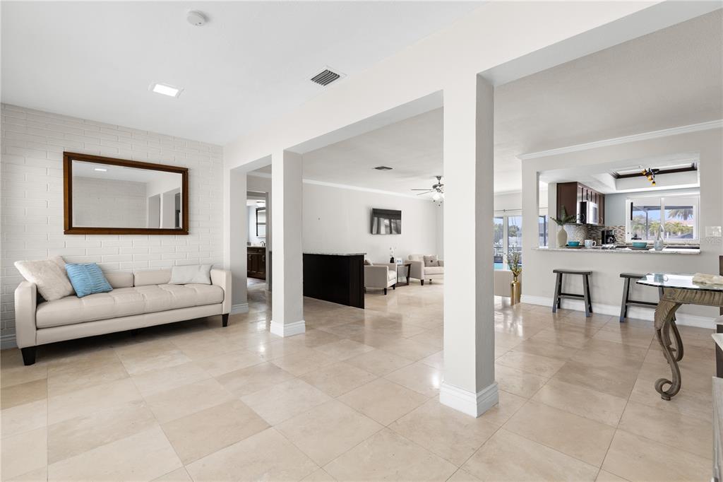 A bright, open-concept living area features light tile flooring, white walls, and a kitchen pass-through — 404 4TH AVENUE N, TIERRA VERDE, FL