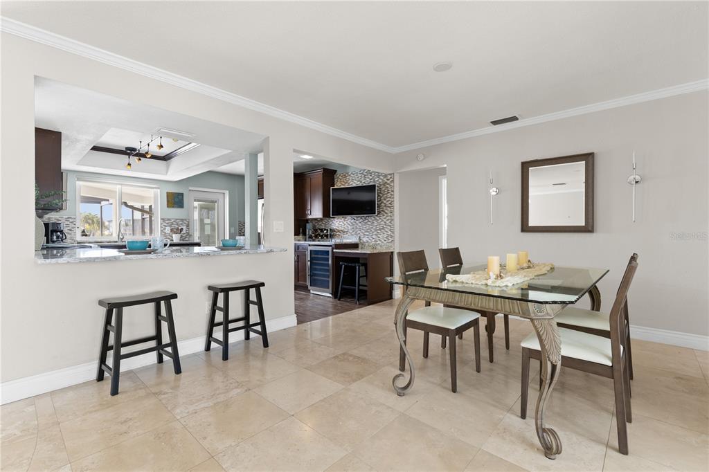 A dining area with a glass table and a kitchen with a breakfast bar — 404 4TH AVENUE N, TIERRA VERDE, FL